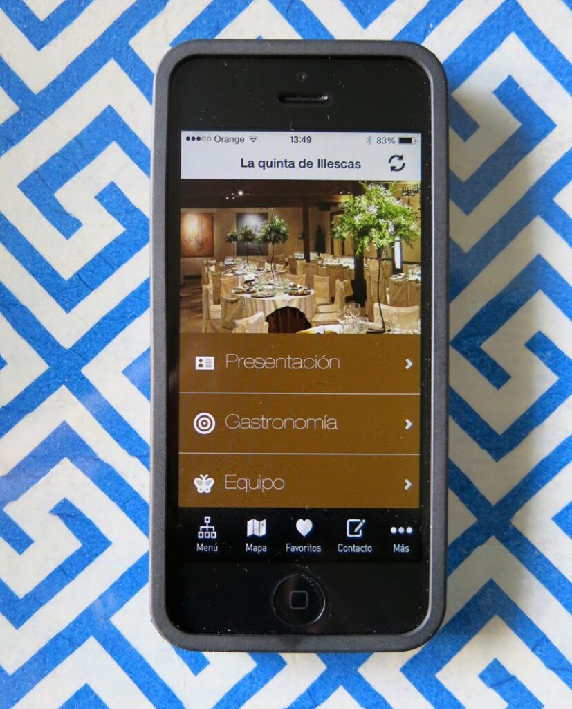 Móvil en el que se puede ver la homepage de la app de La Quinta de Illescas. Aparece una foto del lugar y los distintos apartados.