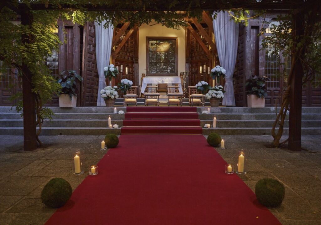 Altar exterior con alfombra roja, velas y arreglos de hortensias blancas en La Quinta de Illescas
