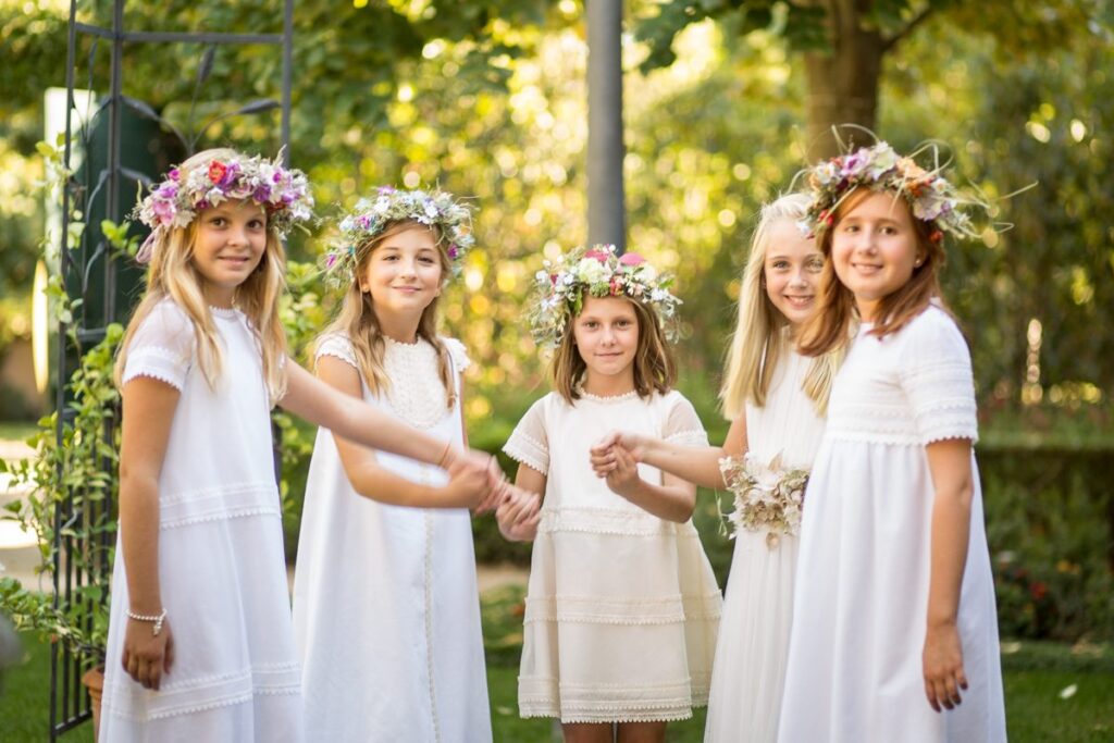 Grupo de niñas vestidas de primera comunión con coronas de flores bohemias.