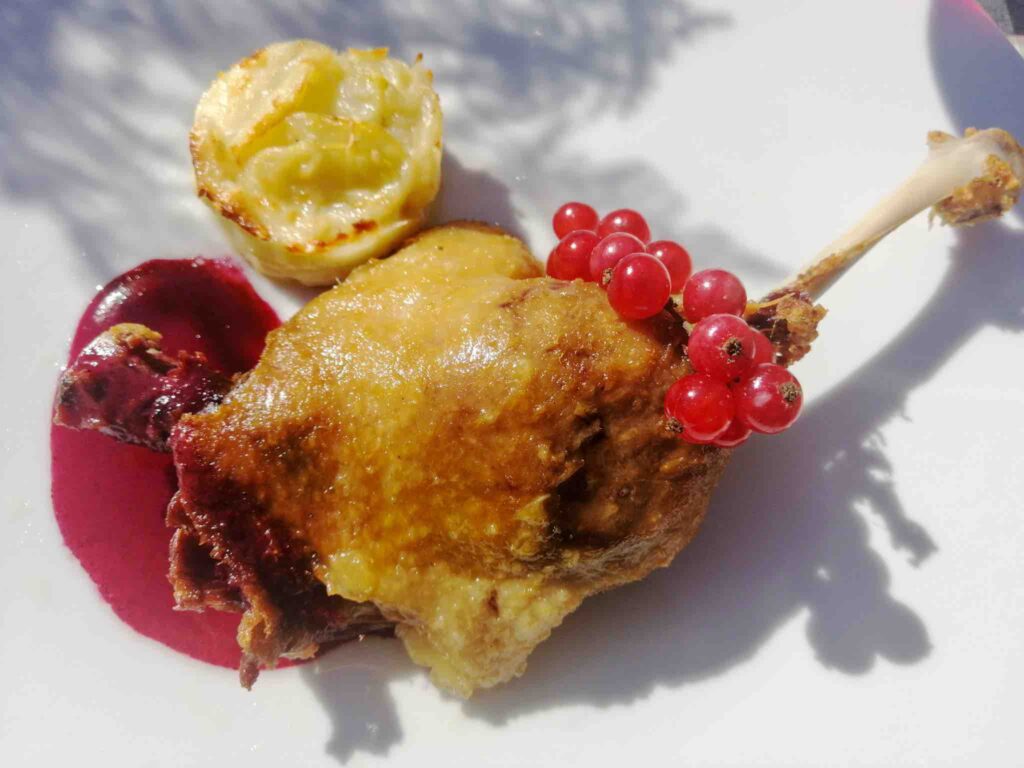 Pato con salsa de frutas rojas y guarnición.