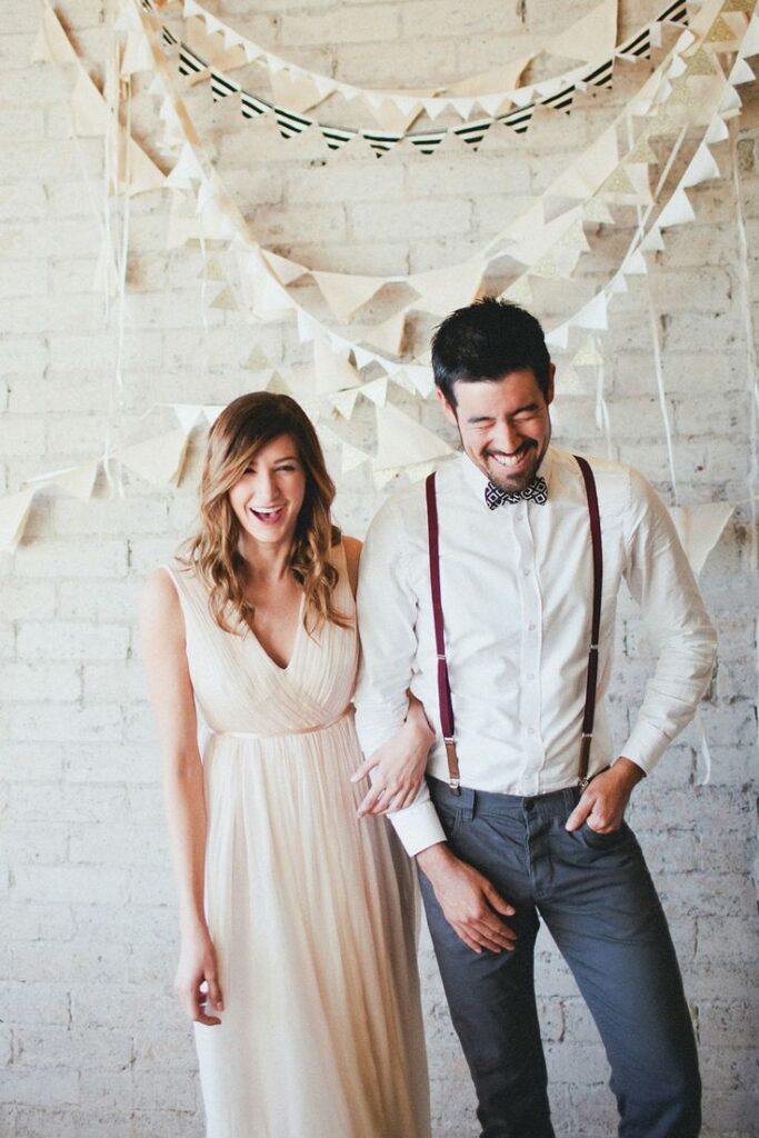 Pareja de novios sonrientes con decoración de banderines de fondo en La Quinta de Illescas