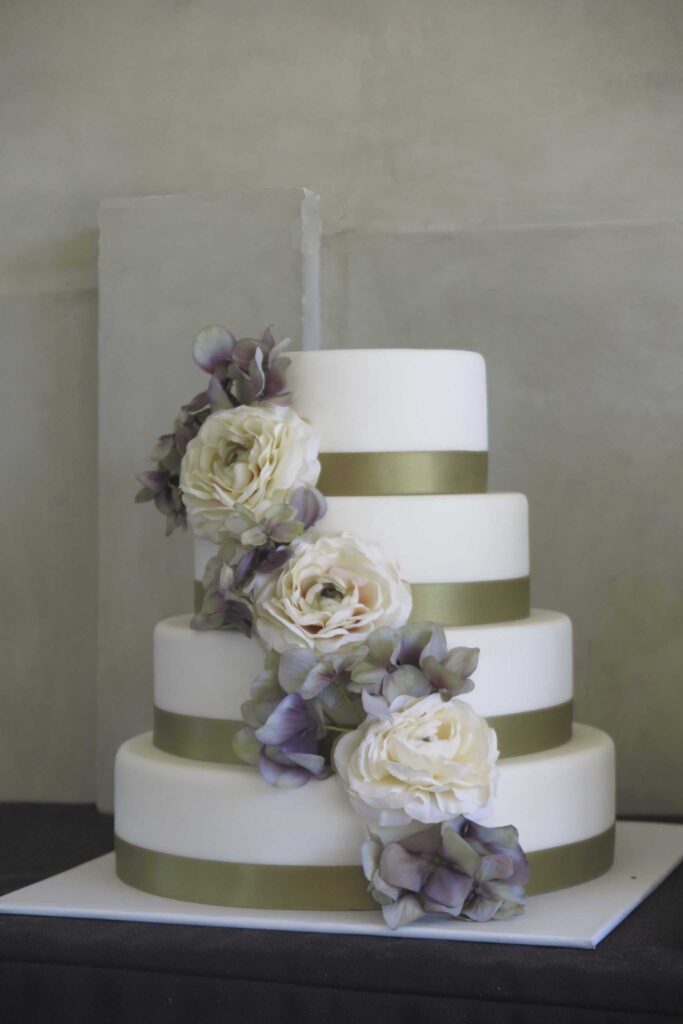 Tarta de boda con detalles dorados y decoración floral.