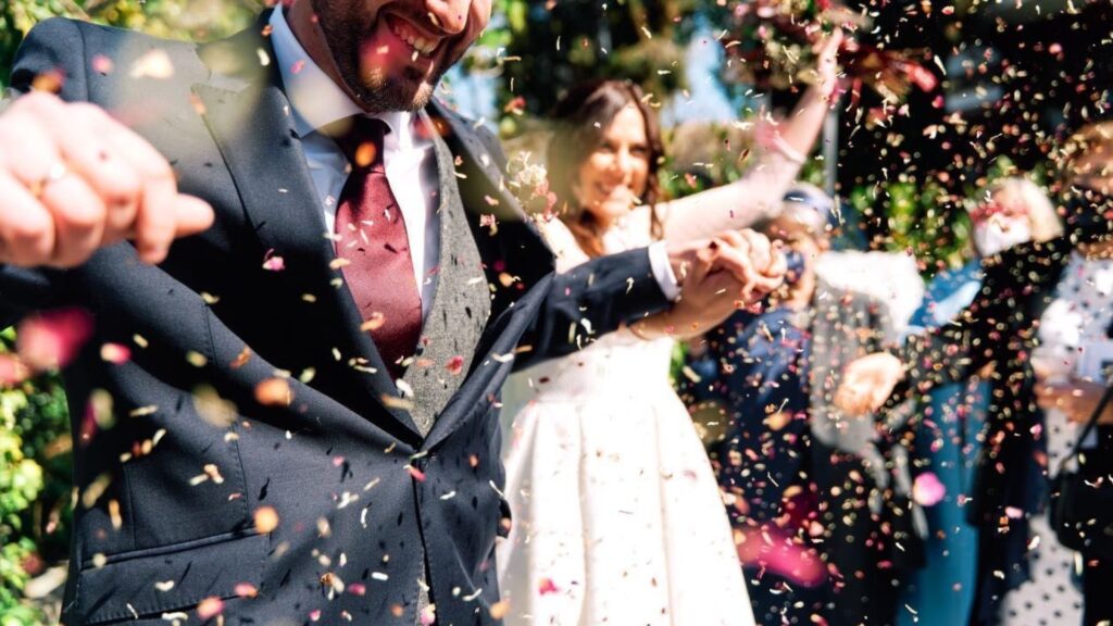 Pareja celebrando su boda rodeada de pétalos de flores.