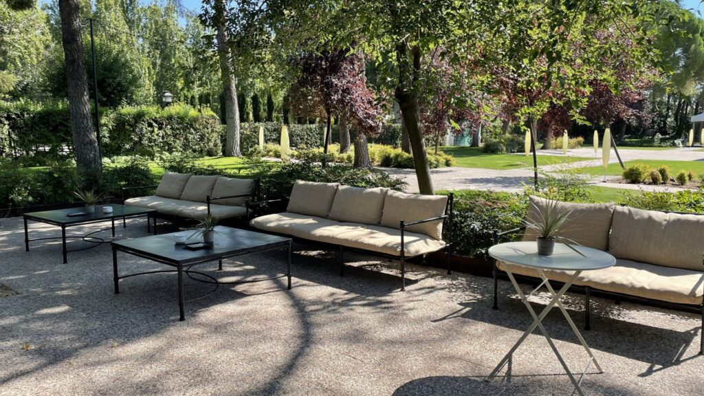 Zona de descanso exterior con sofás y mesas en un jardín.