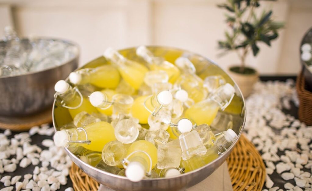 Botellas con bebida amarilla sobre hielo en un recipiente metálico.