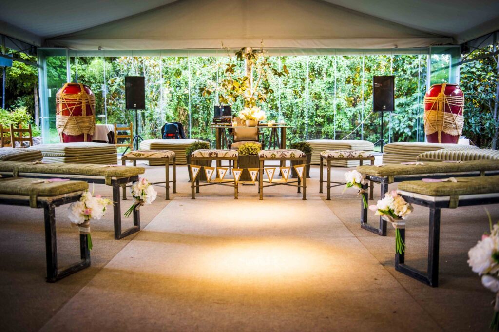 Decoración de ceremonia con bancos, flores y banderines en el altar.