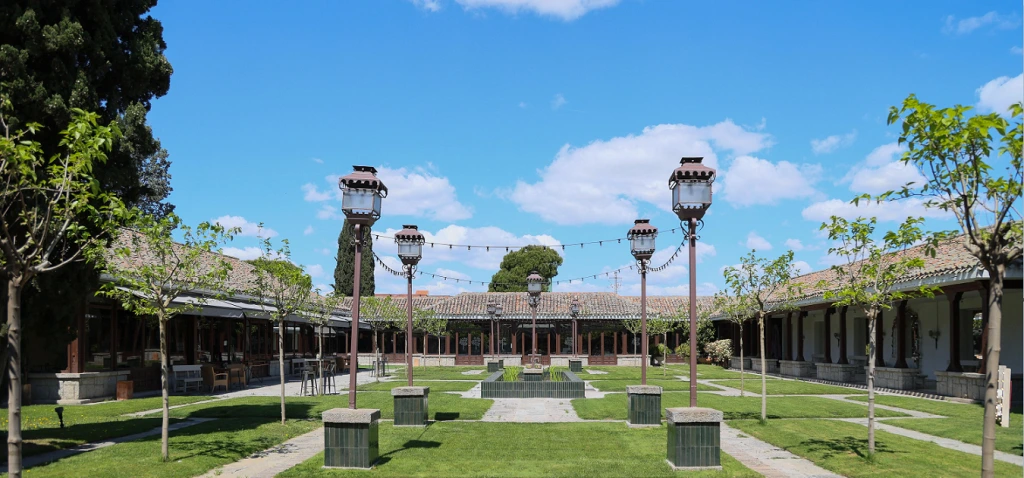 Patio de Los Porches de La Quinta de Illescas con jardines, farolas y galerías porticadas para bodas civiles al aire libre