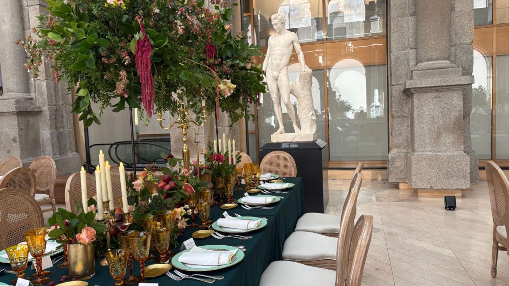 Mesa imperial decorada para evento exclusivo en el Museo Nacional del Prado con candelabros, cristalería dorada y centros florales altos