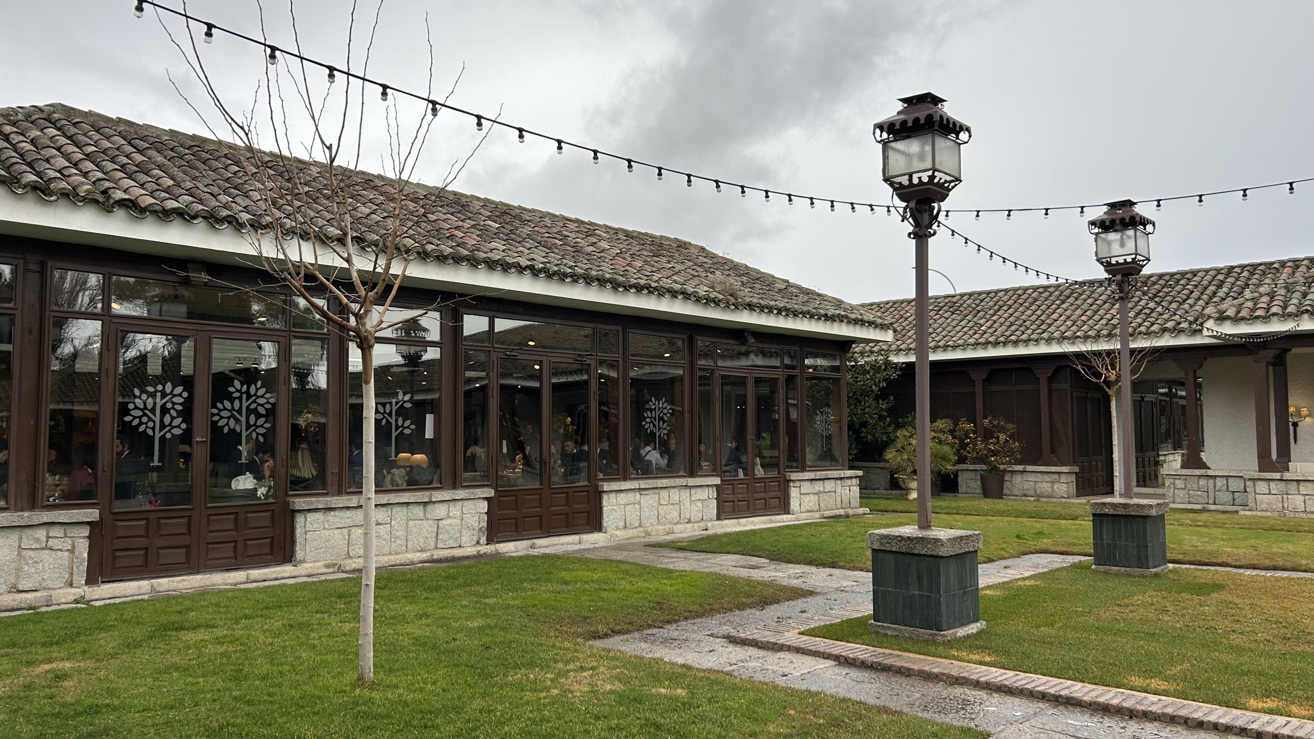 Vista exterior del porche acristalado y el jardín de La Quinta de Illescas en un día nublado