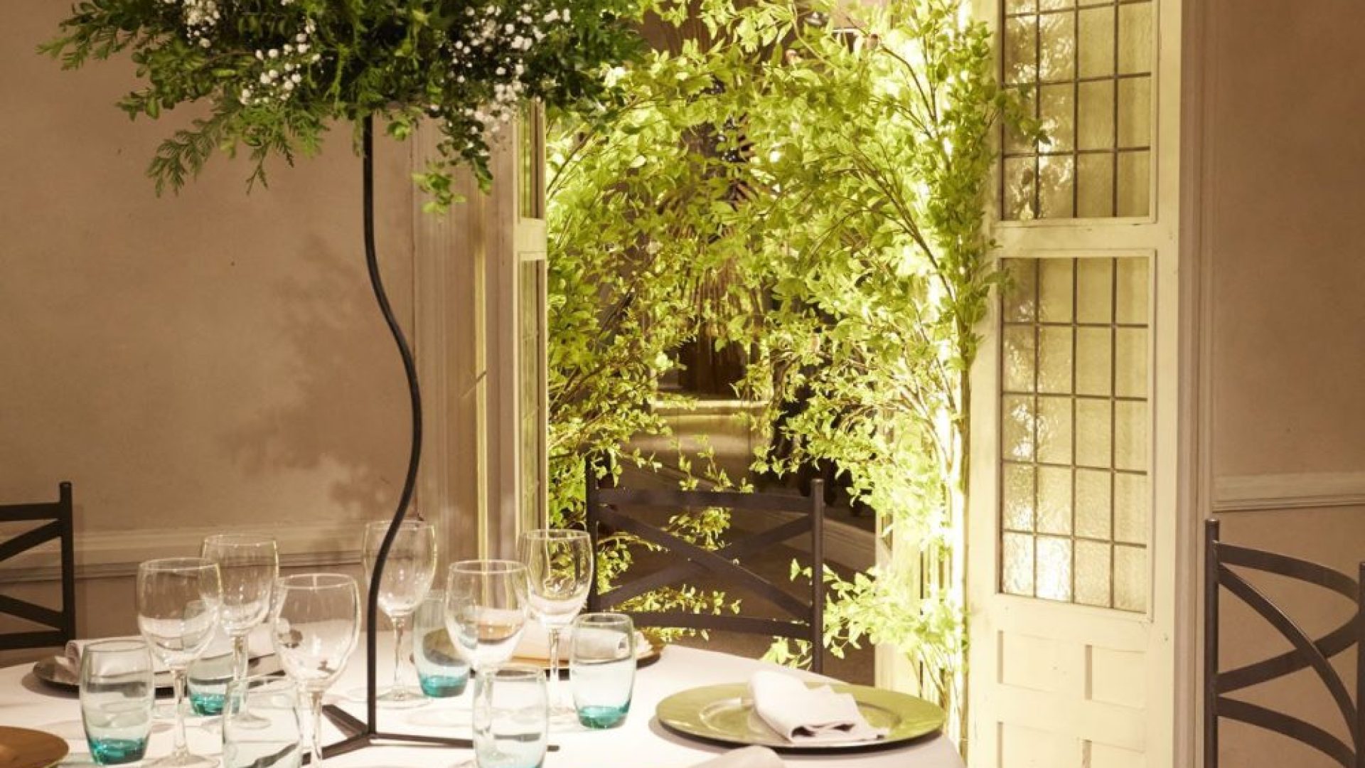 Decoración de mesa con centros florales elevados y sillas de forja en la Quinta de Illescas